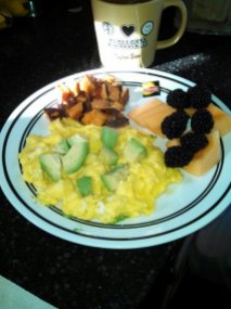 scrambled eggs topped with avocado, cantaloupe and blackberries, roasted sweets